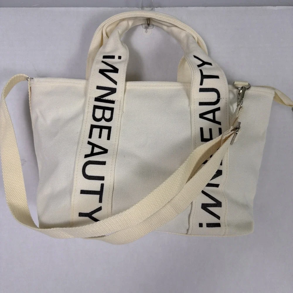 iNN BEAUTY bag off white tote bag with black letter branded straps.